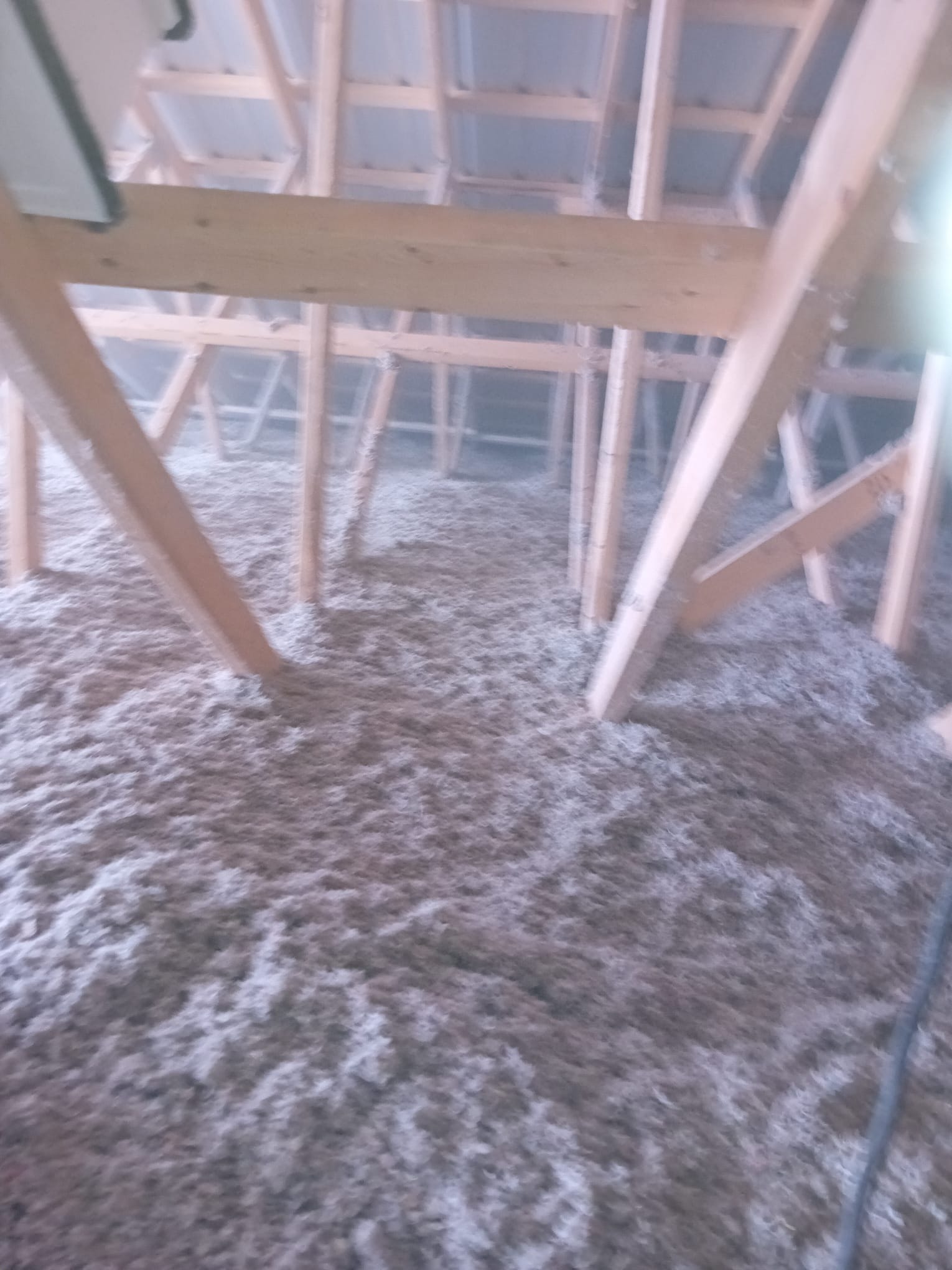 Attic insulation project showing full coverage between trusses